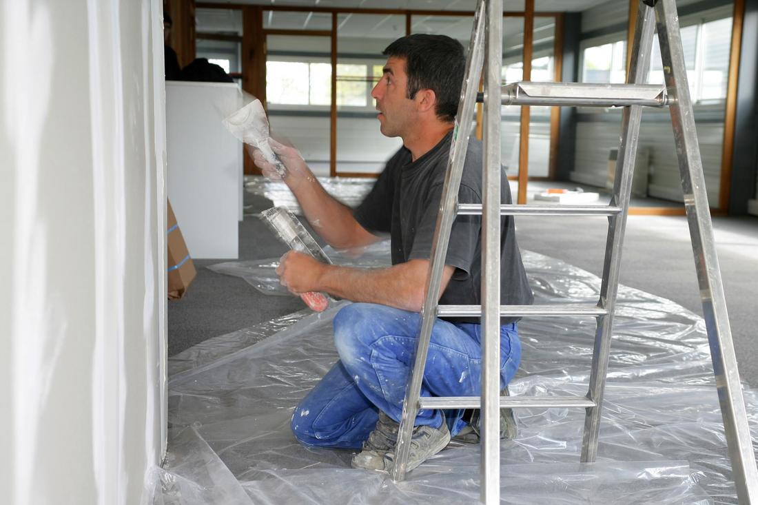 a young man repairing some drywall